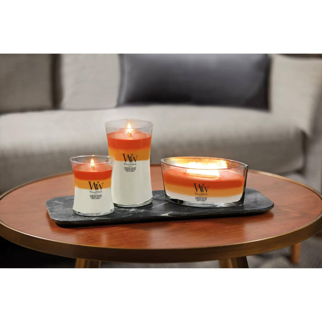 Three lit jar candles on a tray: orange wax in clear glass
