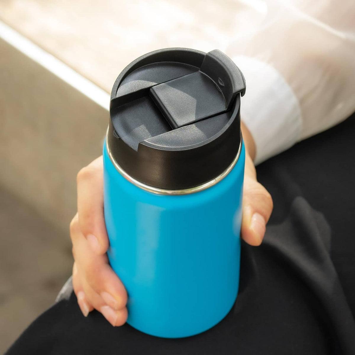 Black flip lid open on bottle, showing cover and drinking opening