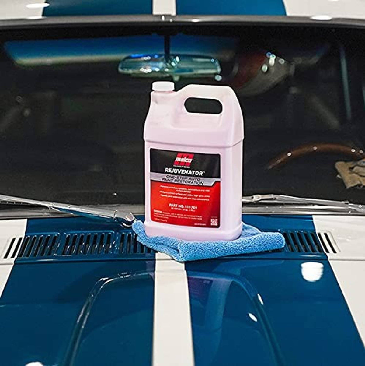 Pink auto paint restoration bottle resting on blue microfiber cloth on car hood
