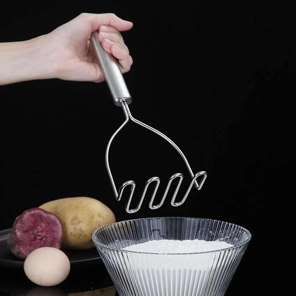 Stainless steel potato masher/ricer held by a long grip above a fine-mesh bowl