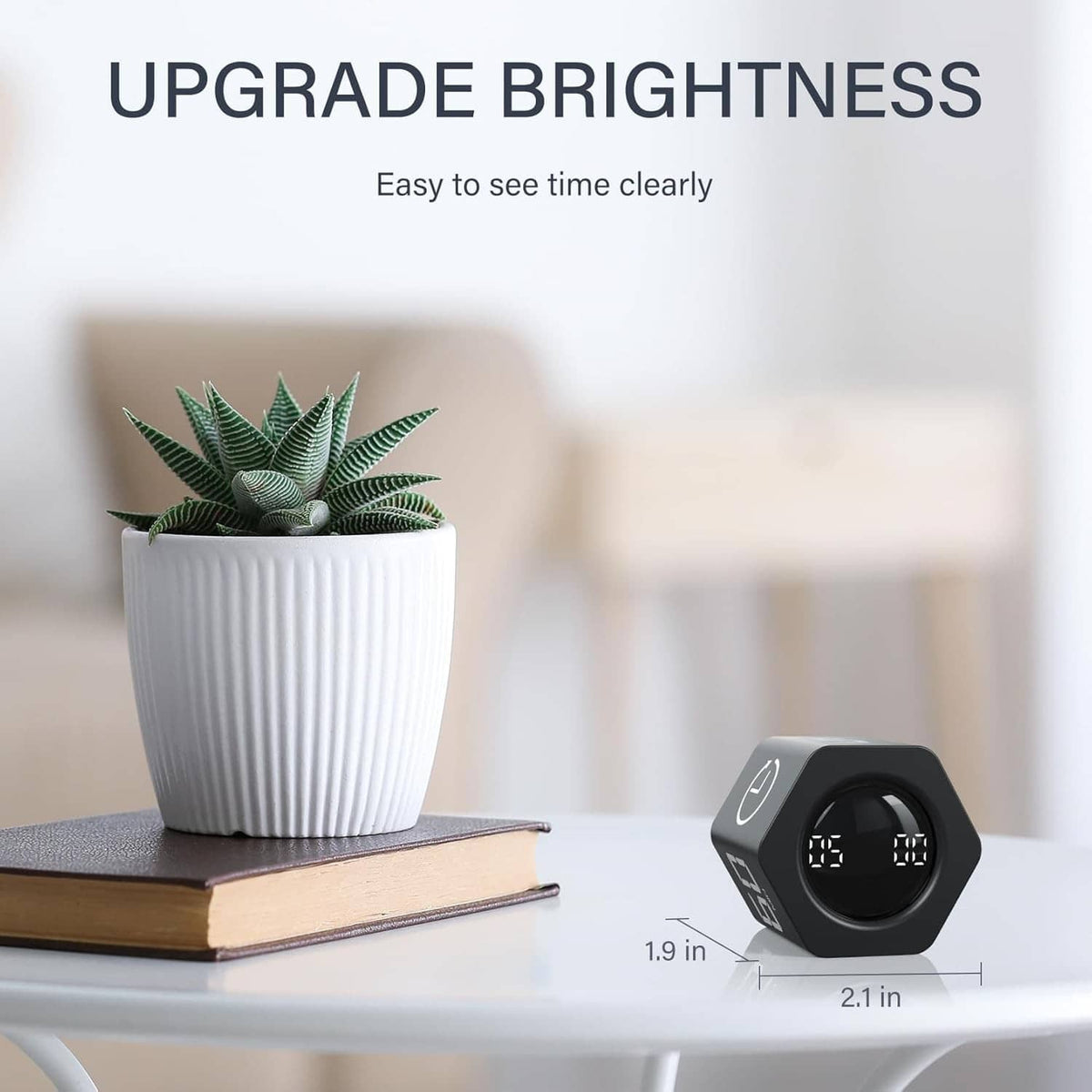 Black rotating timer with bright digital display on a desk beside a potted plant