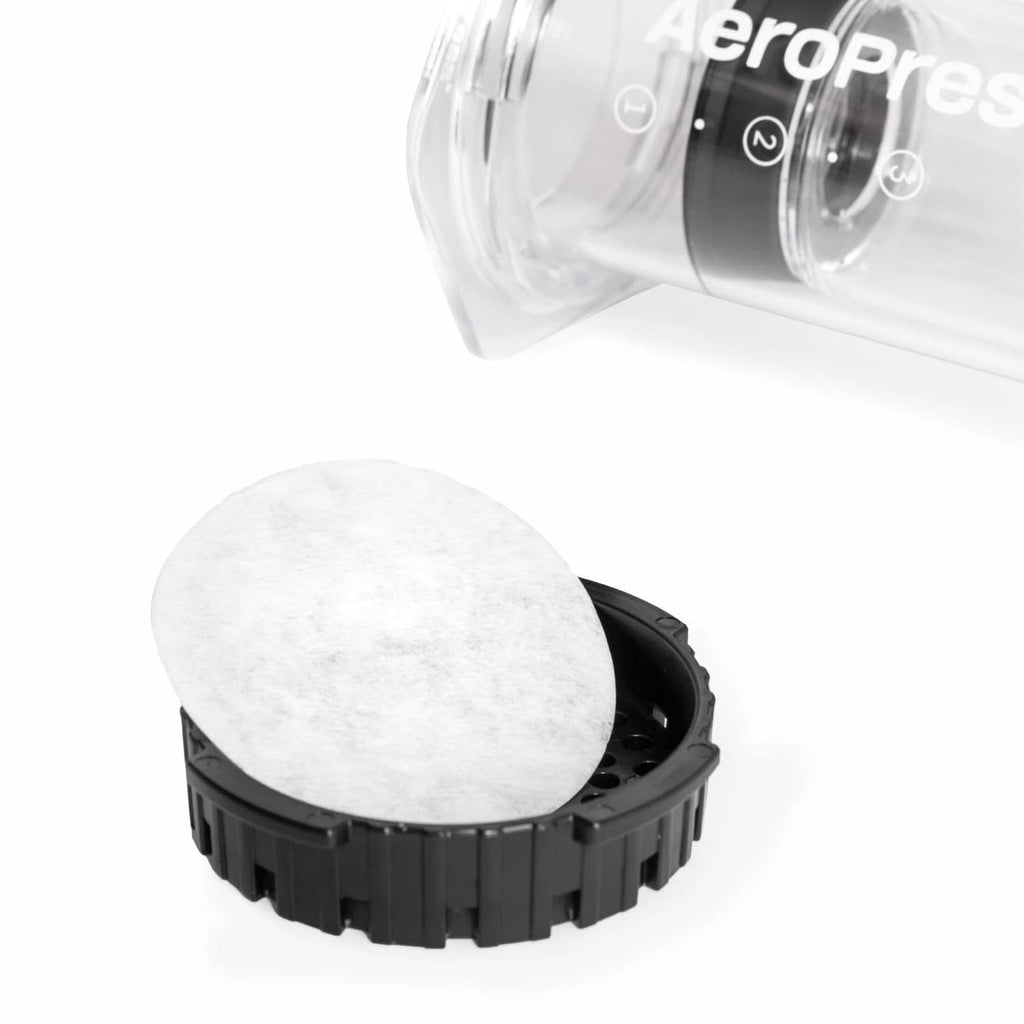 White AeroPress paper filter disc placed in a black filter holder