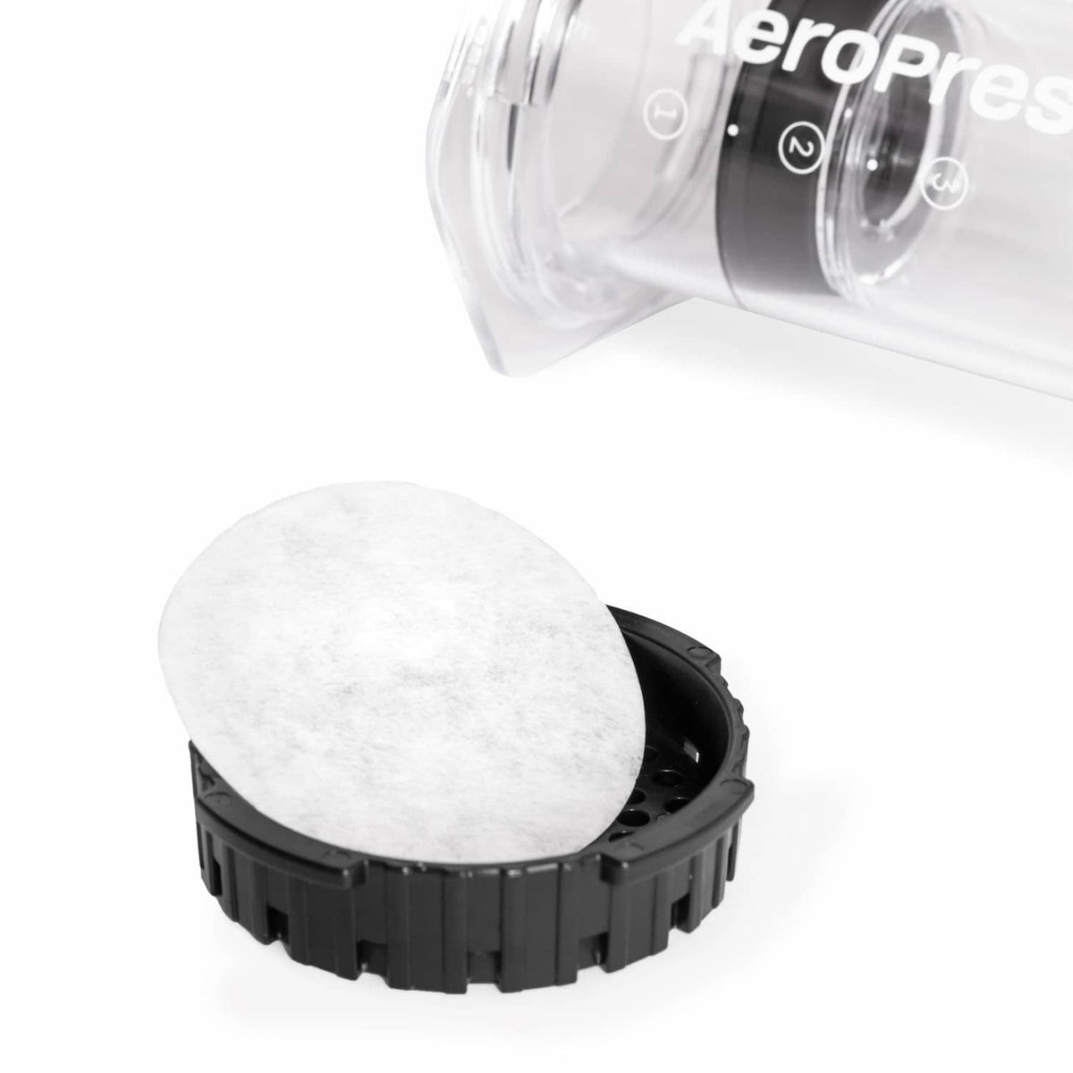 White AeroPress paper filter disc placed in a black filter holder