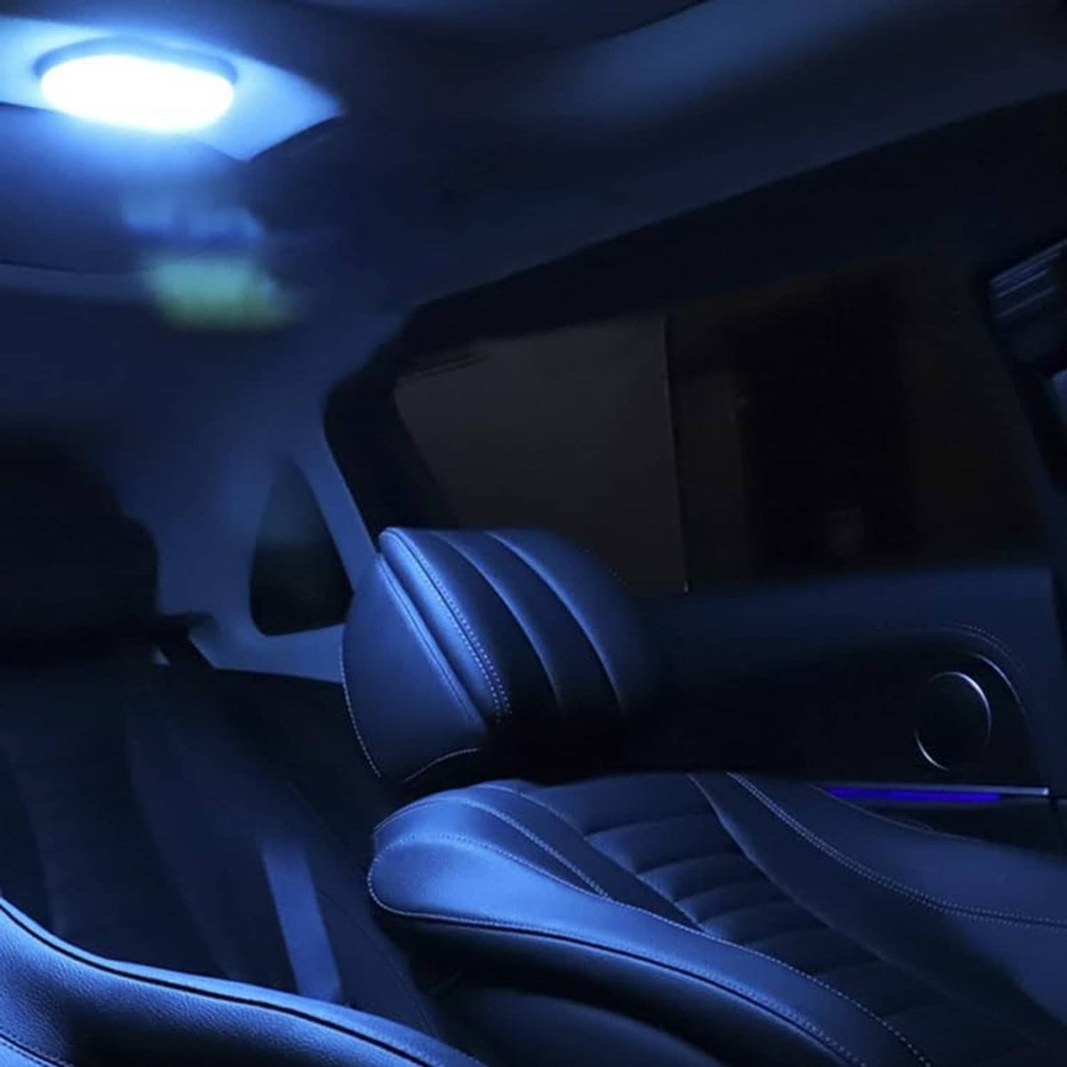 LED dome lamp lit inside a car, overhead light above blue leather seats