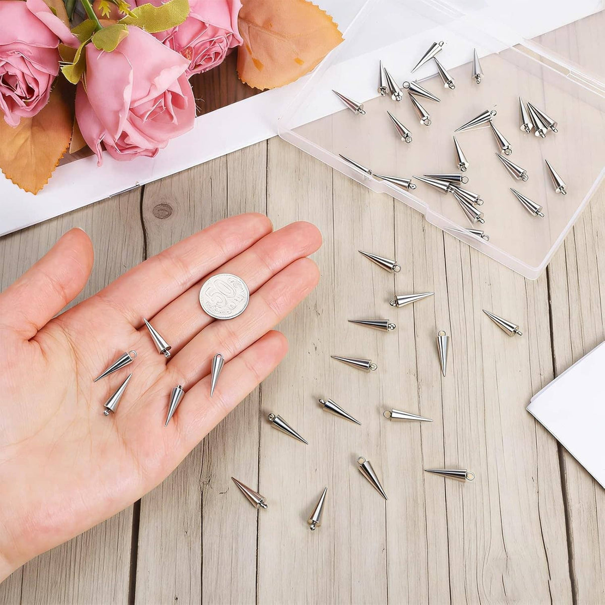 Hand holding stainless steel spike cone charms, small conical spikes with open loops