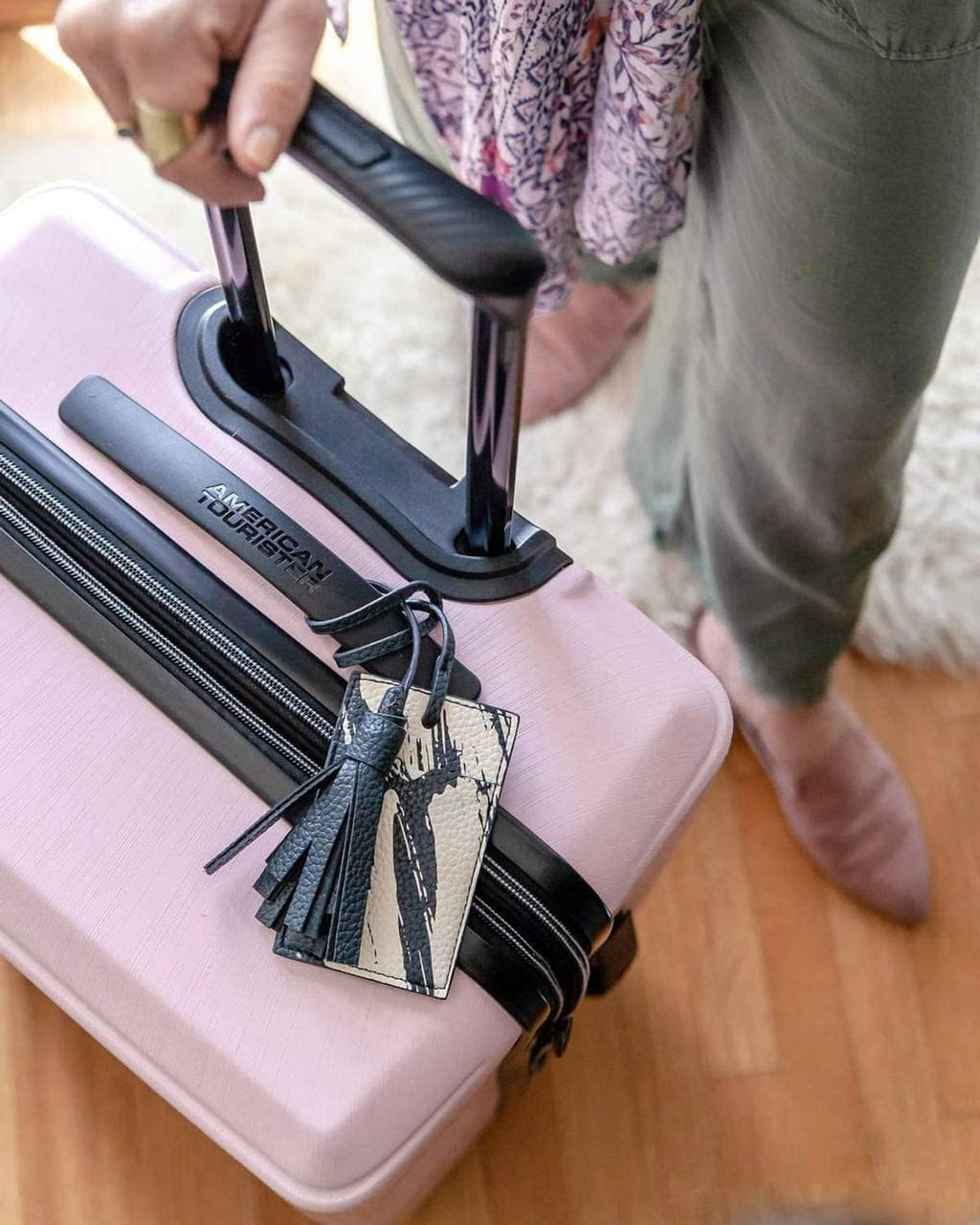 Pink hard-shell luggage with zippers open and black tag charm over inner compartment