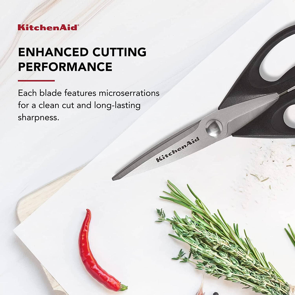 Stainless steel kitchen shears with black handles, cutting blades beside herbs