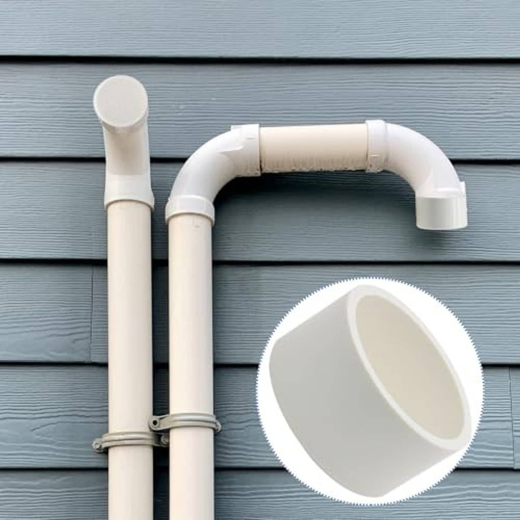 White PVC end cap fitting installed on two-pipe outdoor plumbing setup