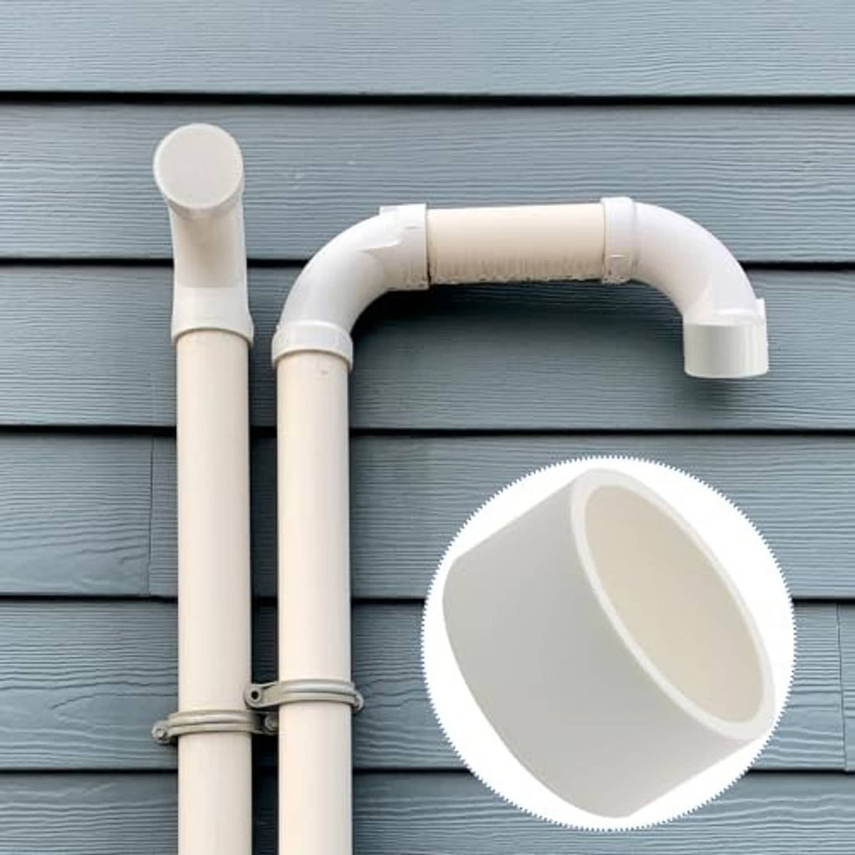 White PVC end cap fitting installed on two-pipe outdoor plumbing setup