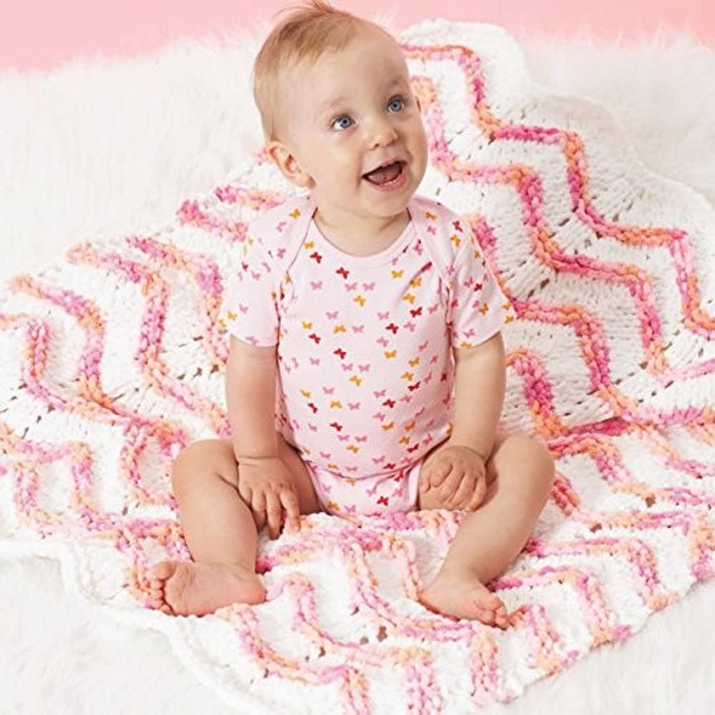 Multicolor chenille baby blanket with wavy stripes, draped on a newborn