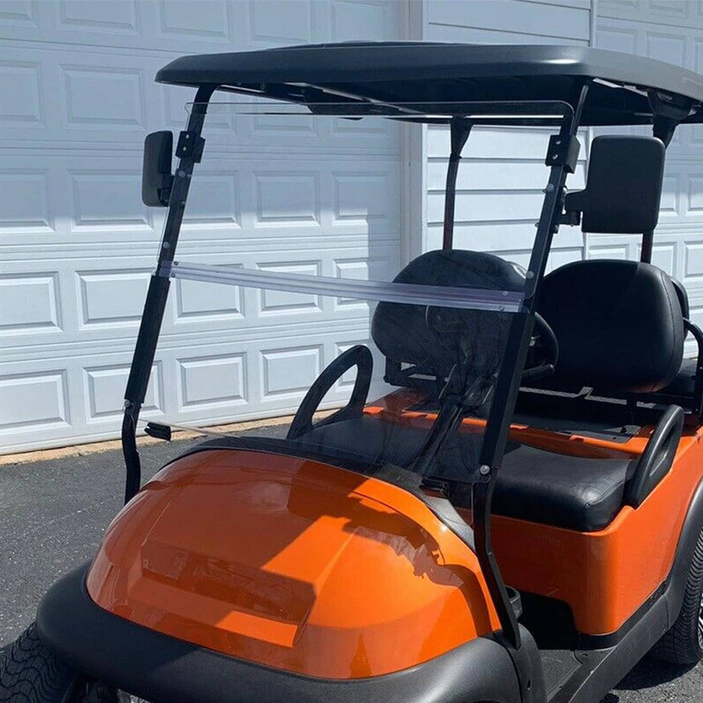 Clear windshield with black frame mounted on an orange golf cart indoors