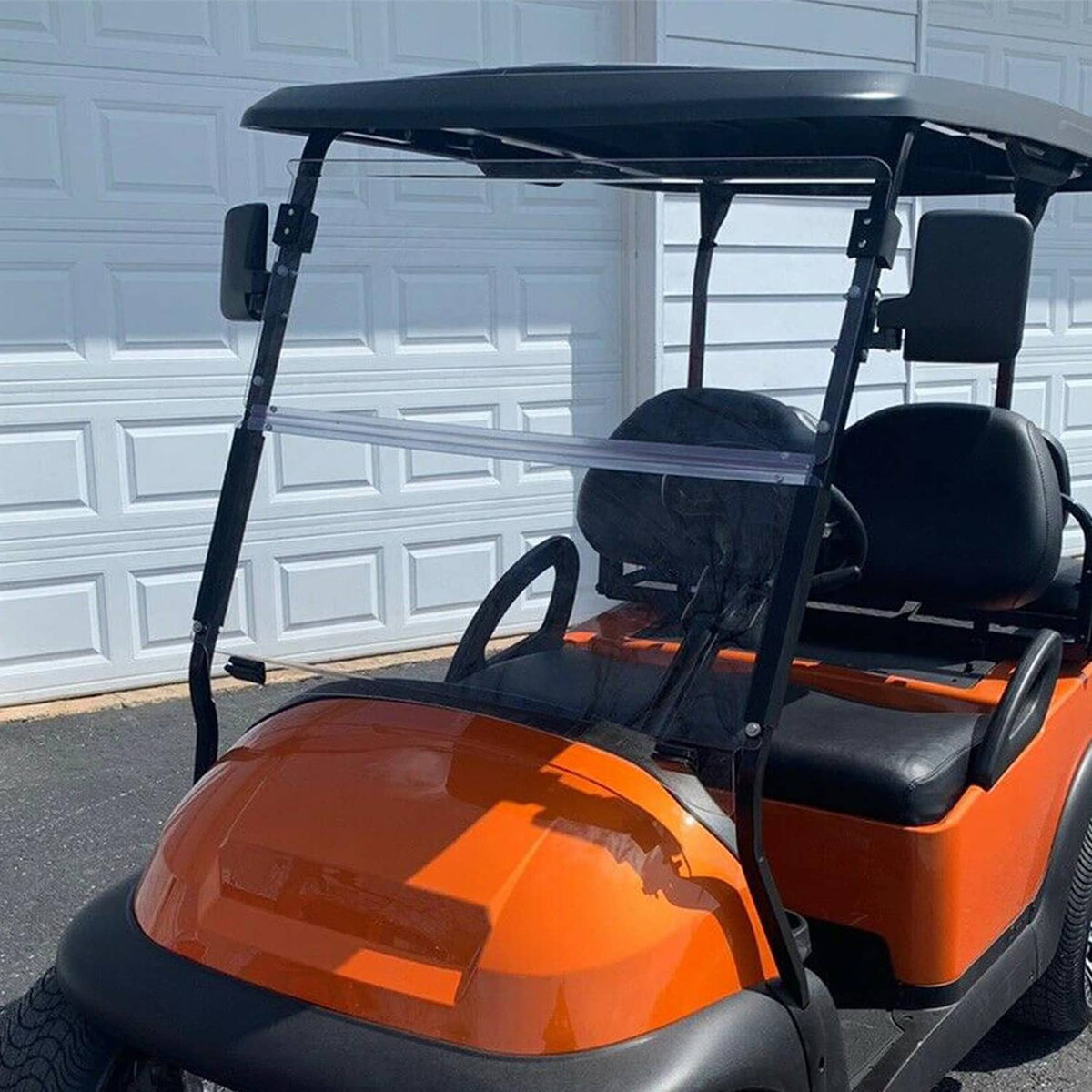 Clear windshield with black frame mounted on an orange golf cart indoors