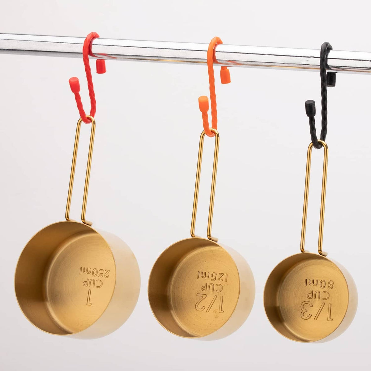 Silicone cable ties securing hanging cookware on a bar, assorted red and black