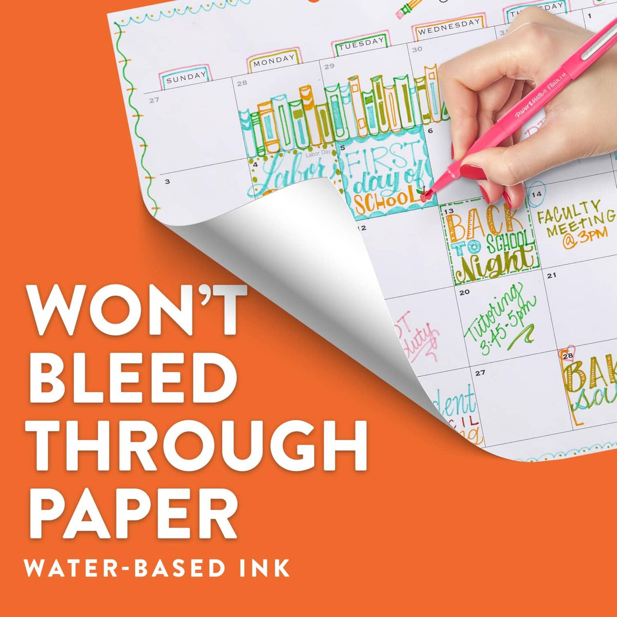 Hand holding a pink felt tip pen writing on a paper calendar