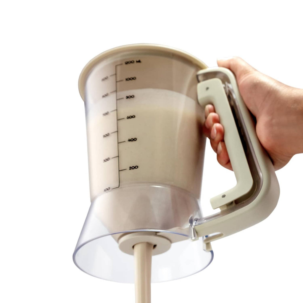 Beige batter dispenser with side handle and lid, measurement scale on clear cup