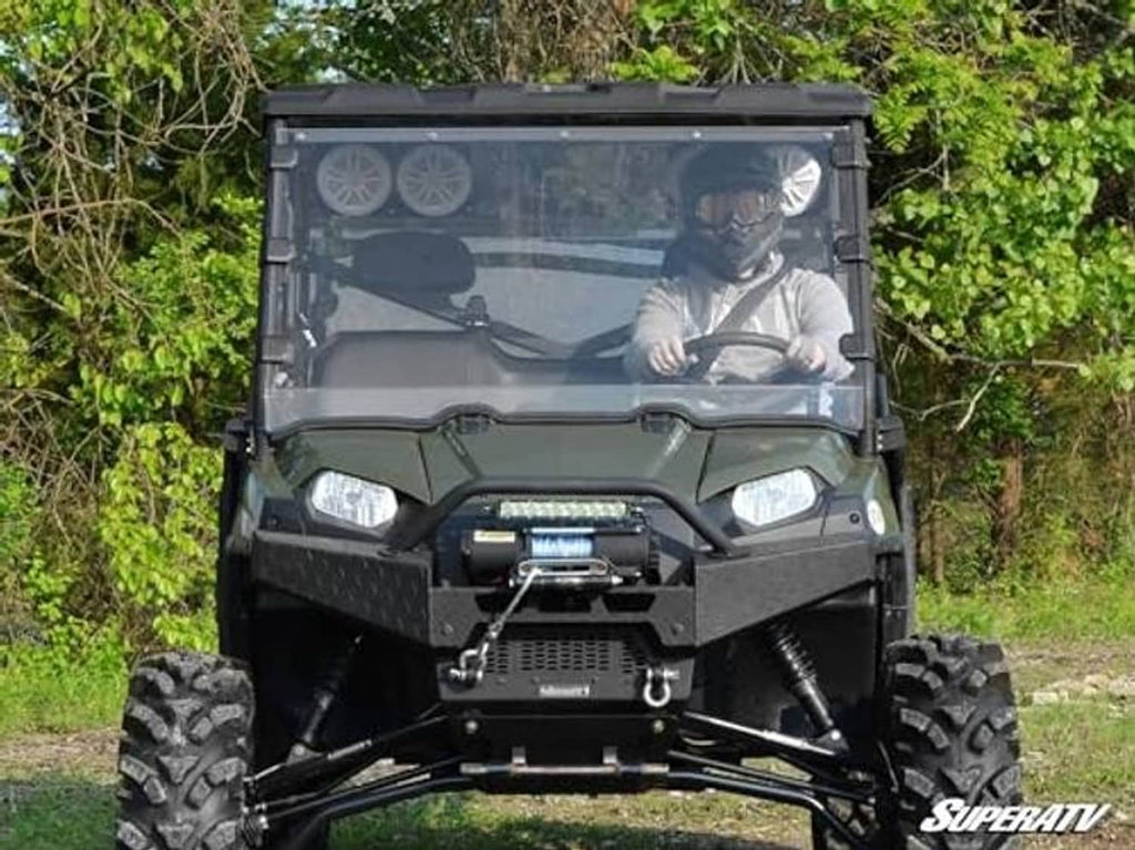 Clear full windshield on green UTV, front view outdoors with driver inside