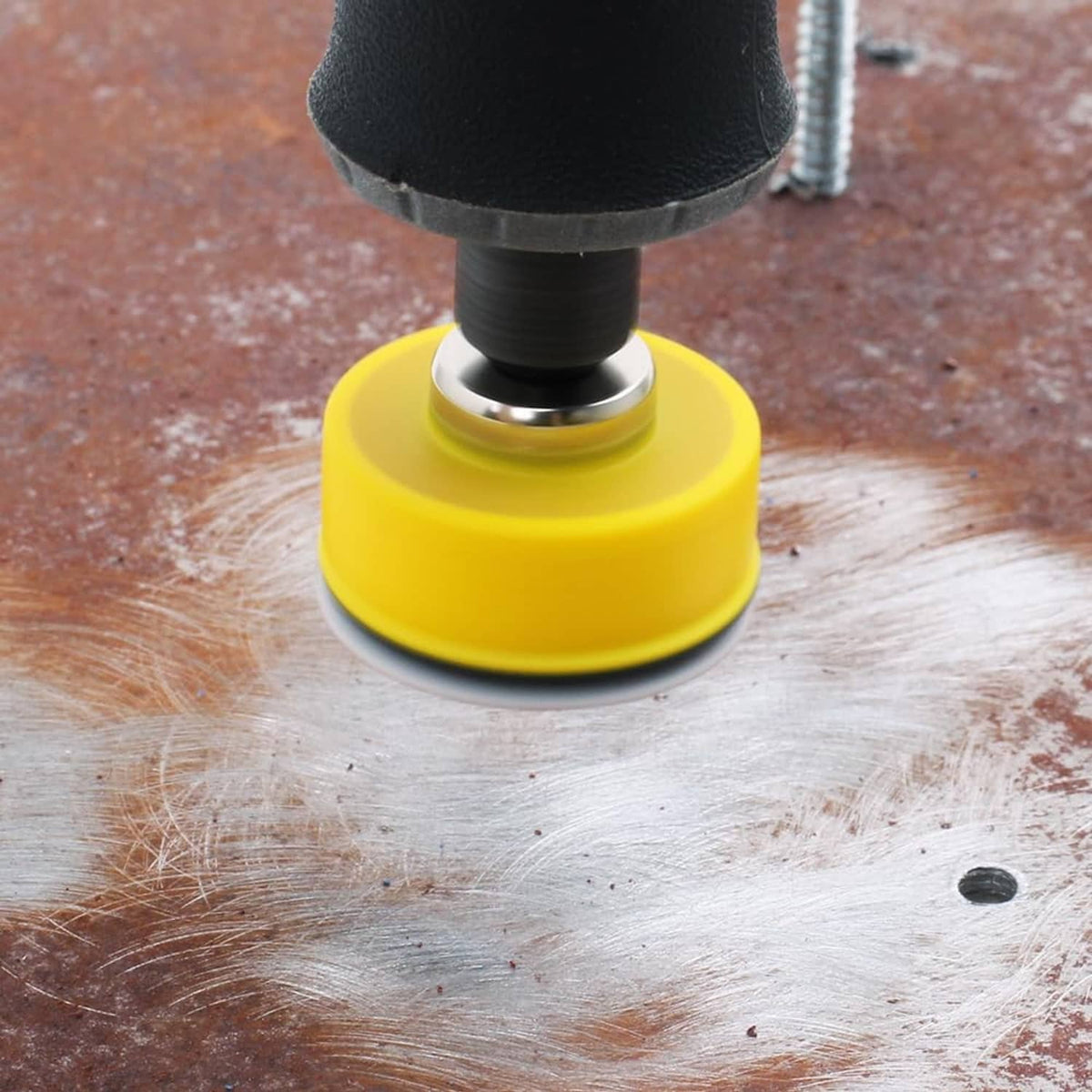 Yellow-backed sanding disc on wood surface with spinning tool for detail sanding