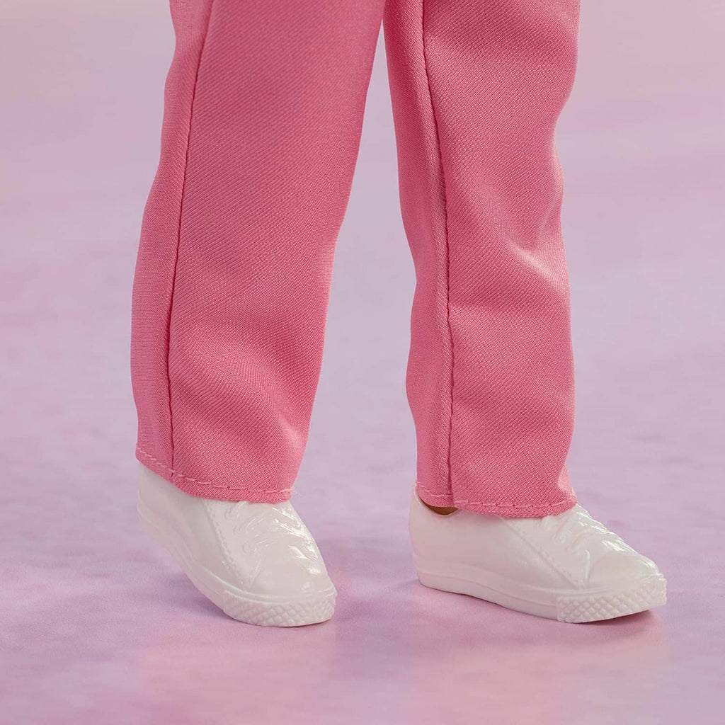 Collectible doll legs wearing pink pants with stitched seams and white sneakers