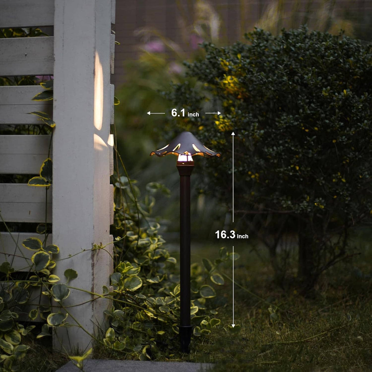 Two low-voltage LED pathway lights standing along a walkway beside shrubs