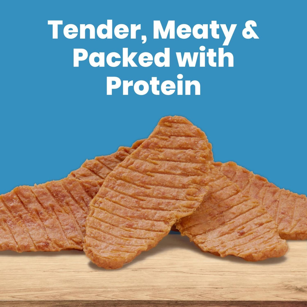 Chicken jerky cuts dog treats, orange-brown strips on a light wood surface