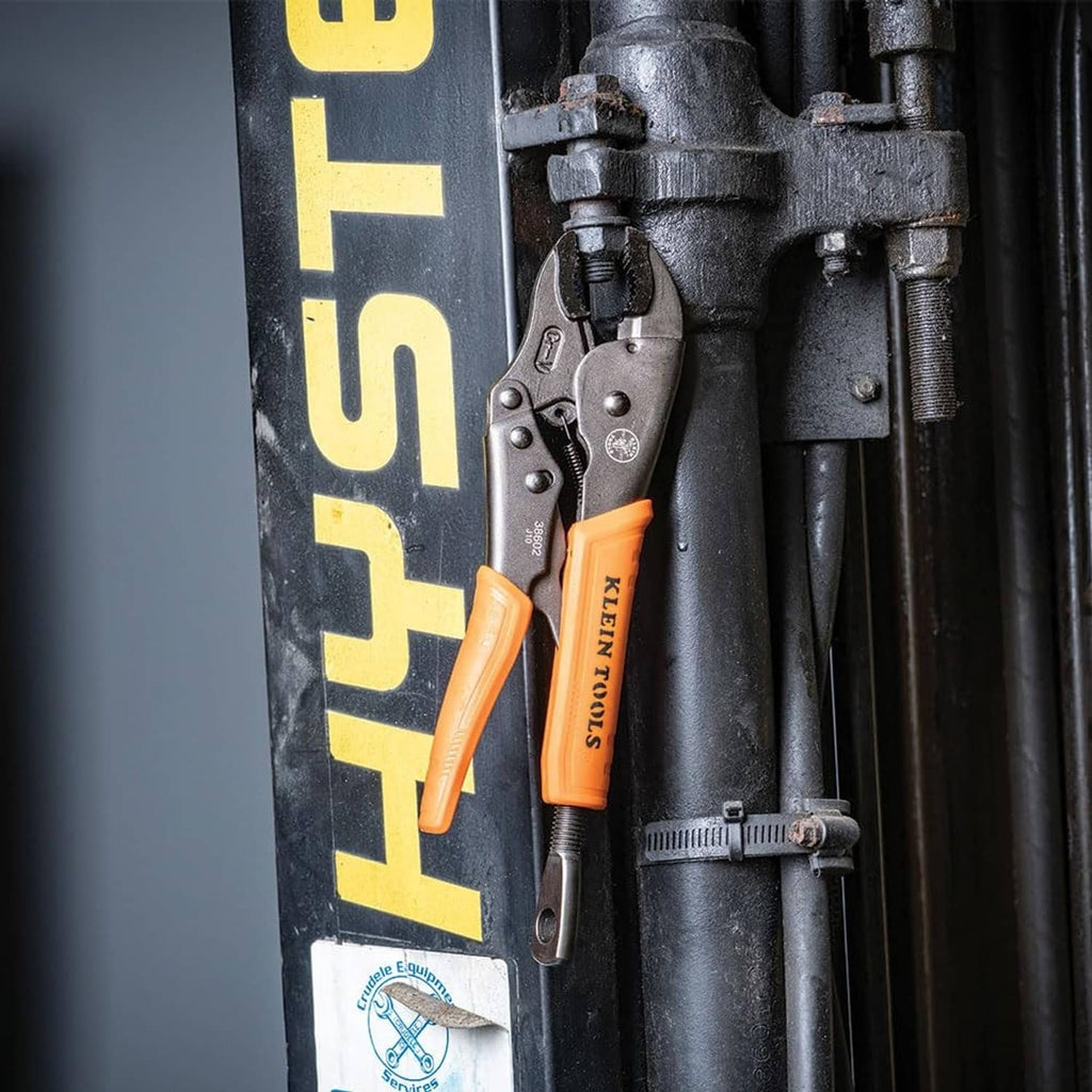 Orange-and-black locking pliers on a metal and plastic tool setup