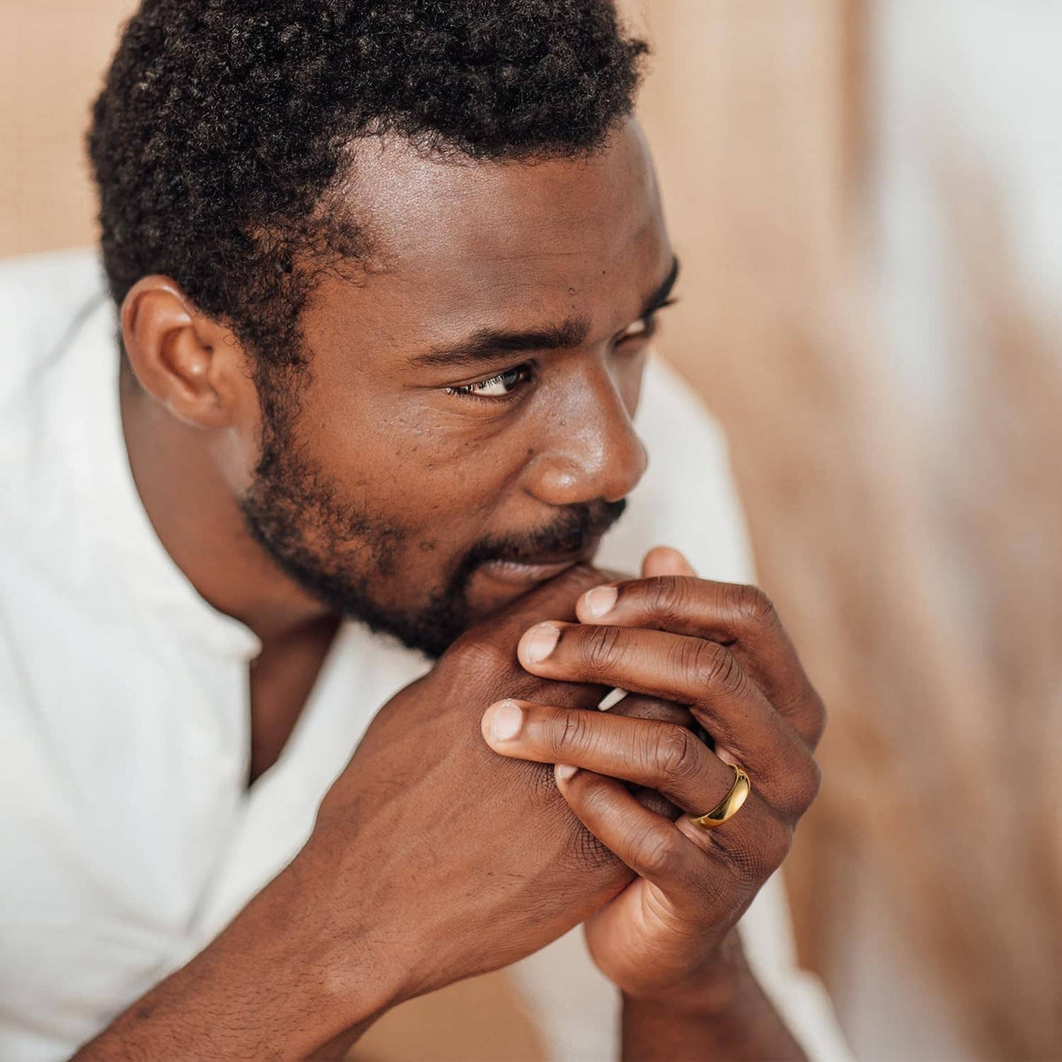 Man holding hand near face, gold plated tungsten carbide ring on finger