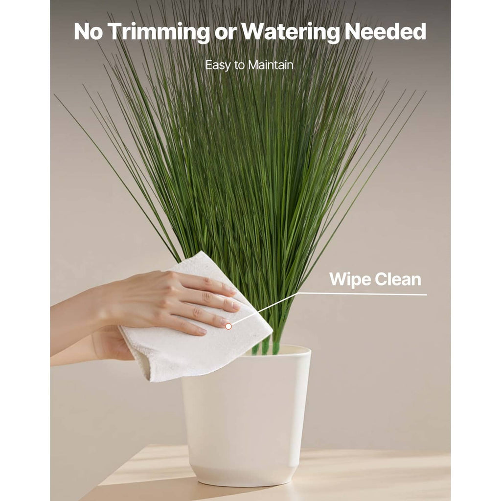 Artificial onion grass plant in white pot with green blades, cleaned with cloth