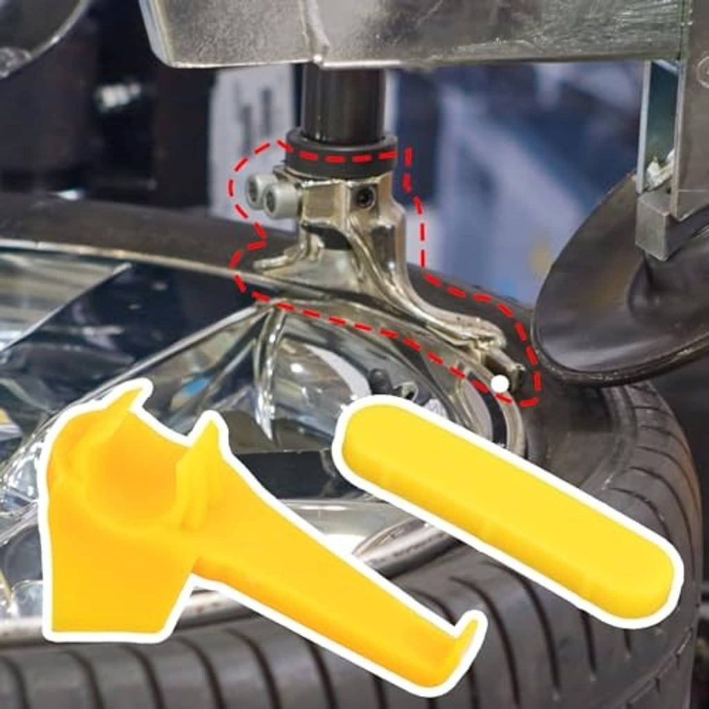 Yellow duck-head inserts installed on a tire changer tool near the wheel rim