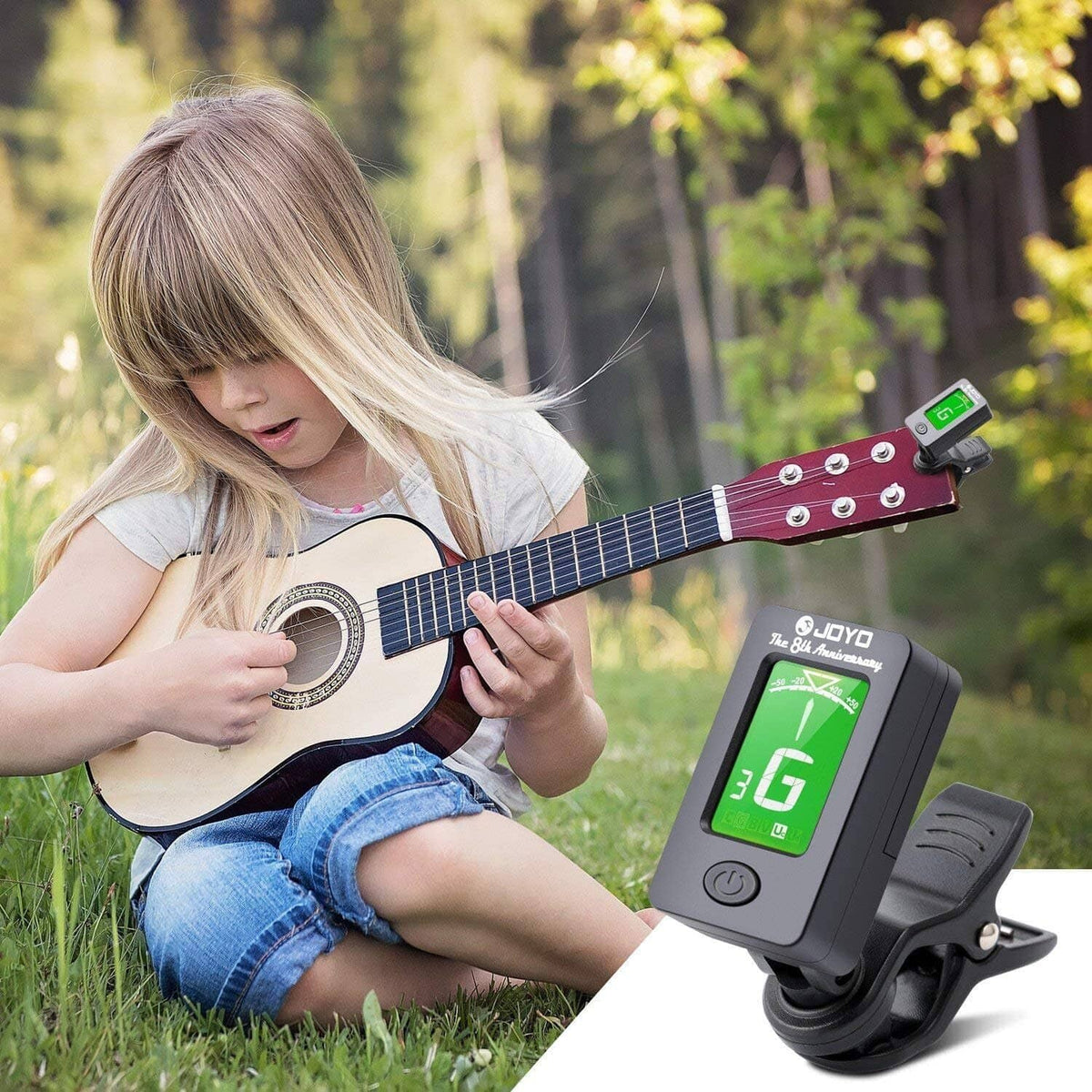 Clip-on tuner capo on a ukulele headstock, LCD displays G note