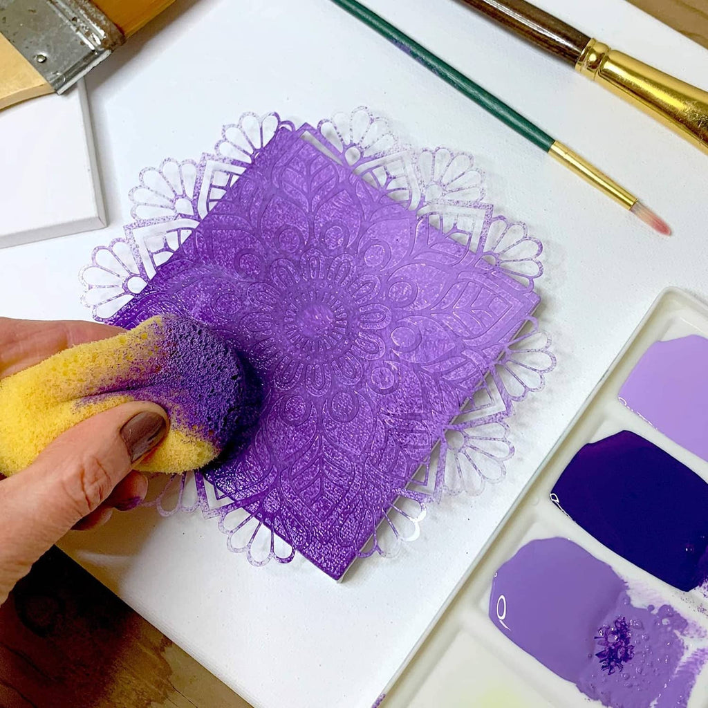 Purple ornate stencil sheet with doily pattern, held by hand