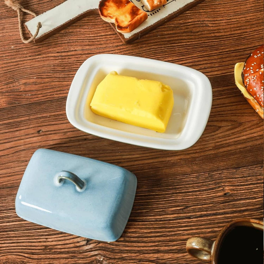Blue ceramic butter dish with lid open; tray holding a stick of butter