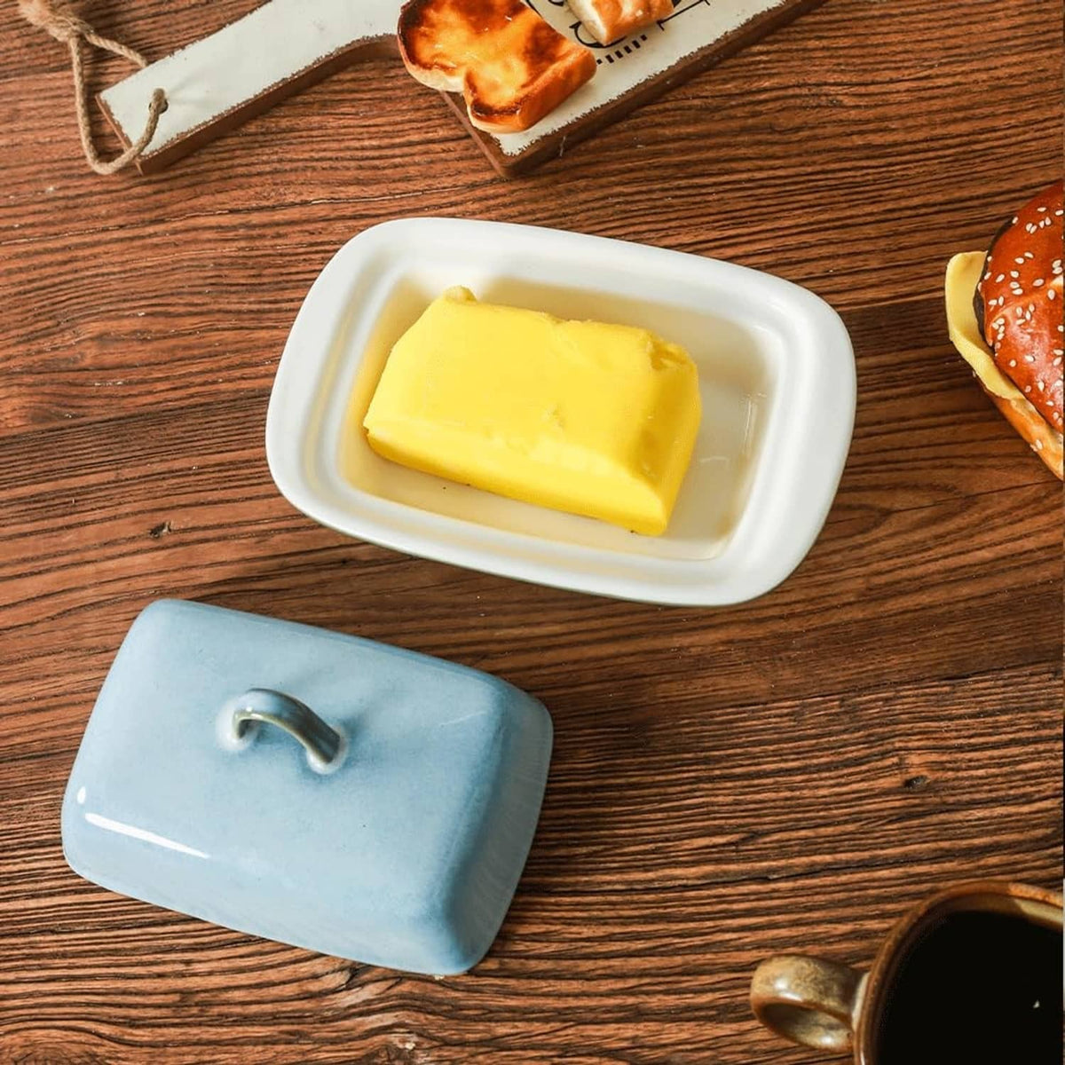 Blue ceramic butter dish with lid open; tray holding a stick of butter