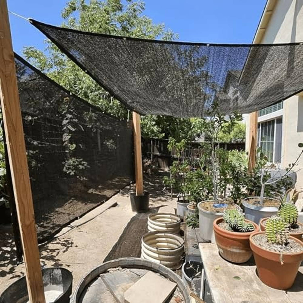 Dark gray shade net stretched over garden plants on wooden posts