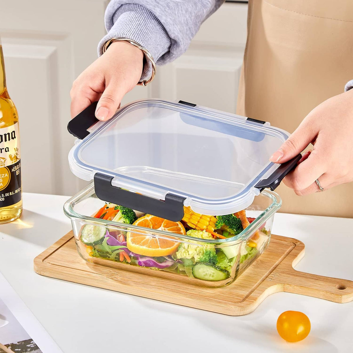 Clear glass food container with blue-tinted lid being closed with black latch