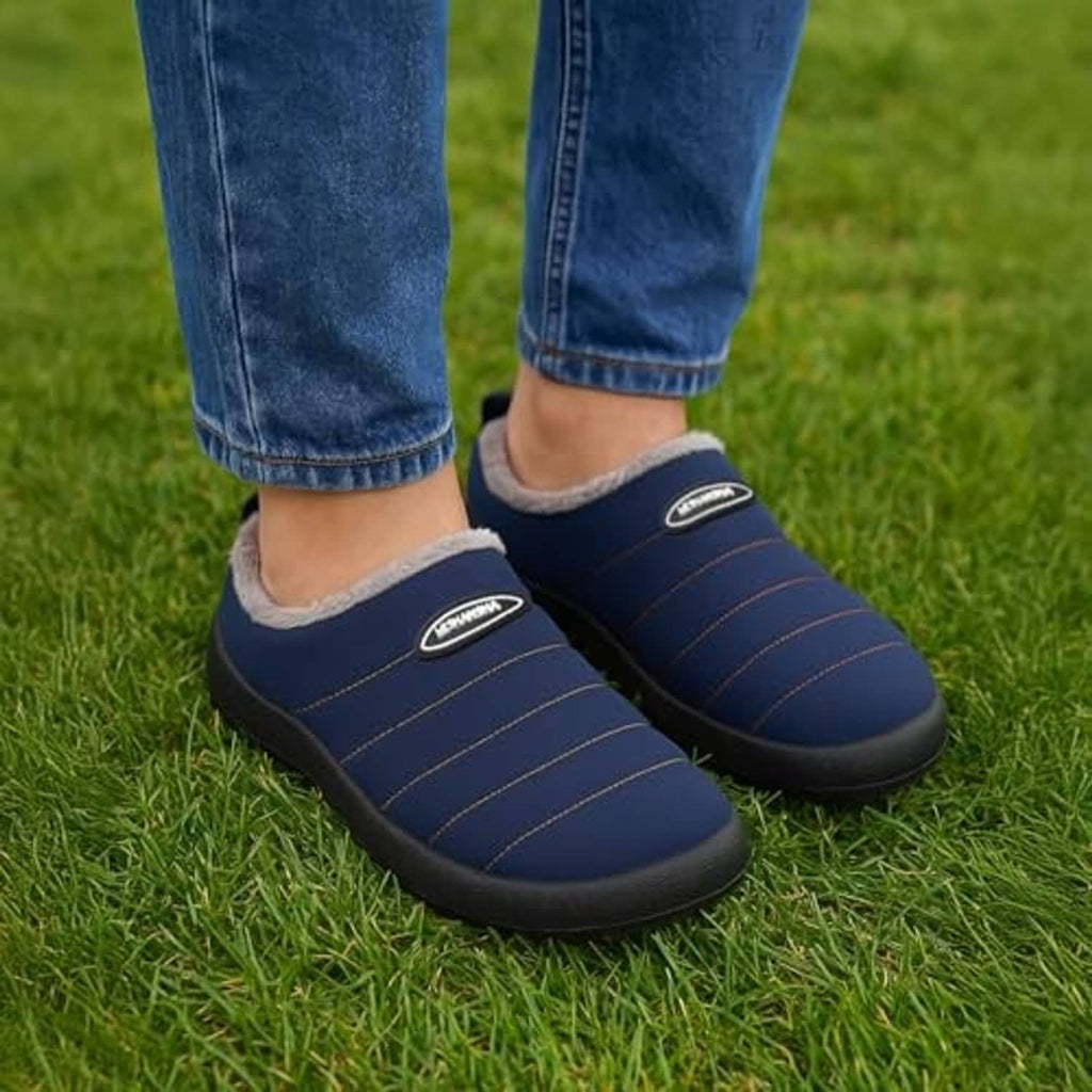 Dark blue faux-fur lined house slippers worn with blue jeans on grass