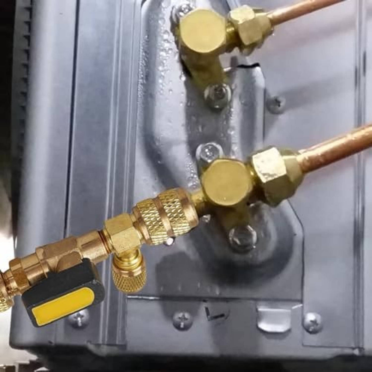 Brass valve core remover installed on an air-conditioning valve line with dual fittings