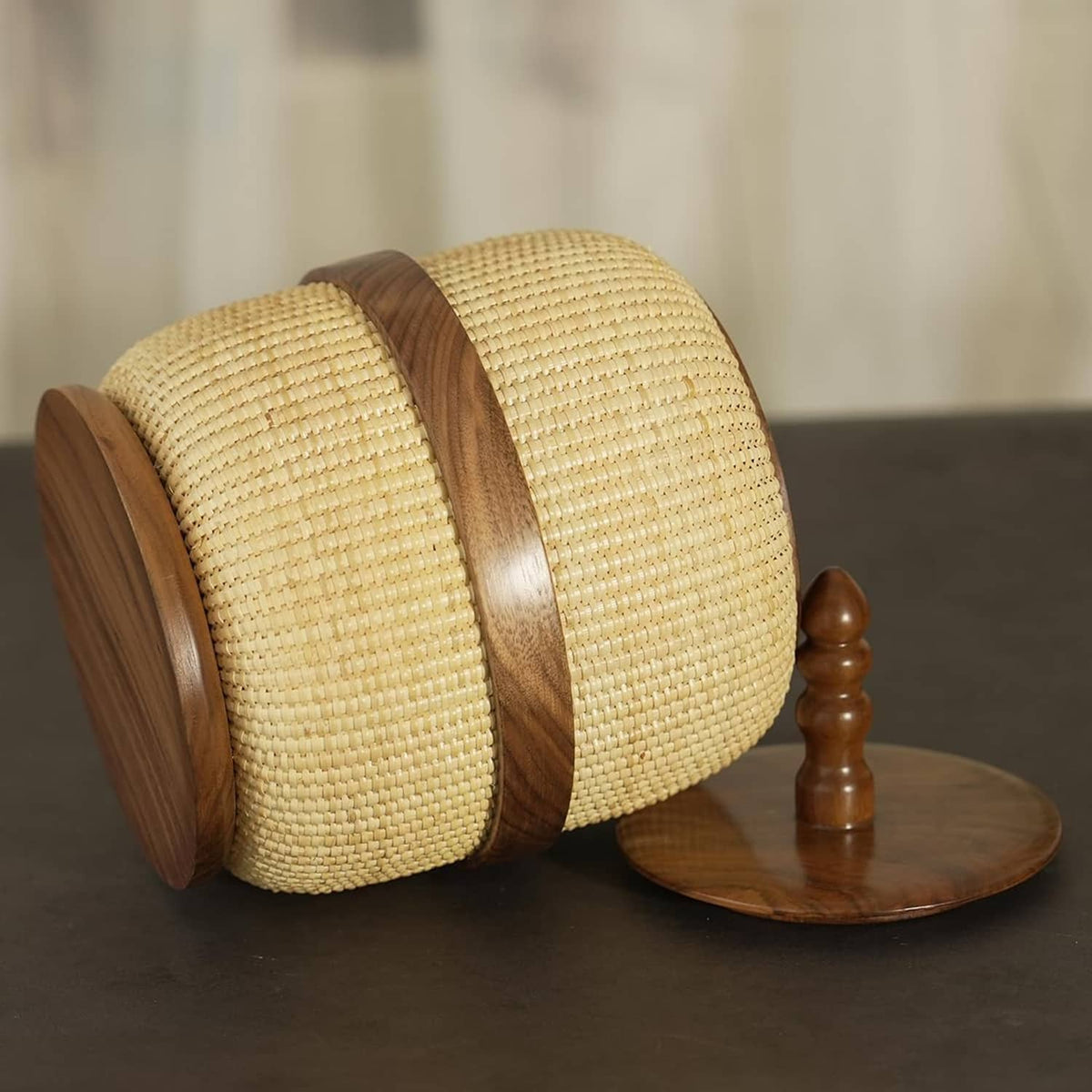 Lidded woven rattan storage basket with dark wooden band, side view, yellow beige
