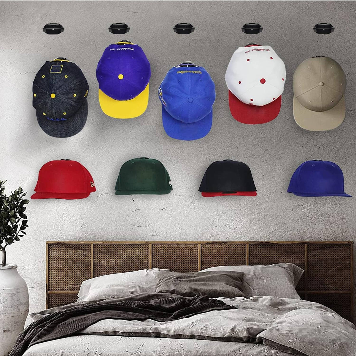 Assorted baseball caps secured by black adhesive hat hooks on a wall
