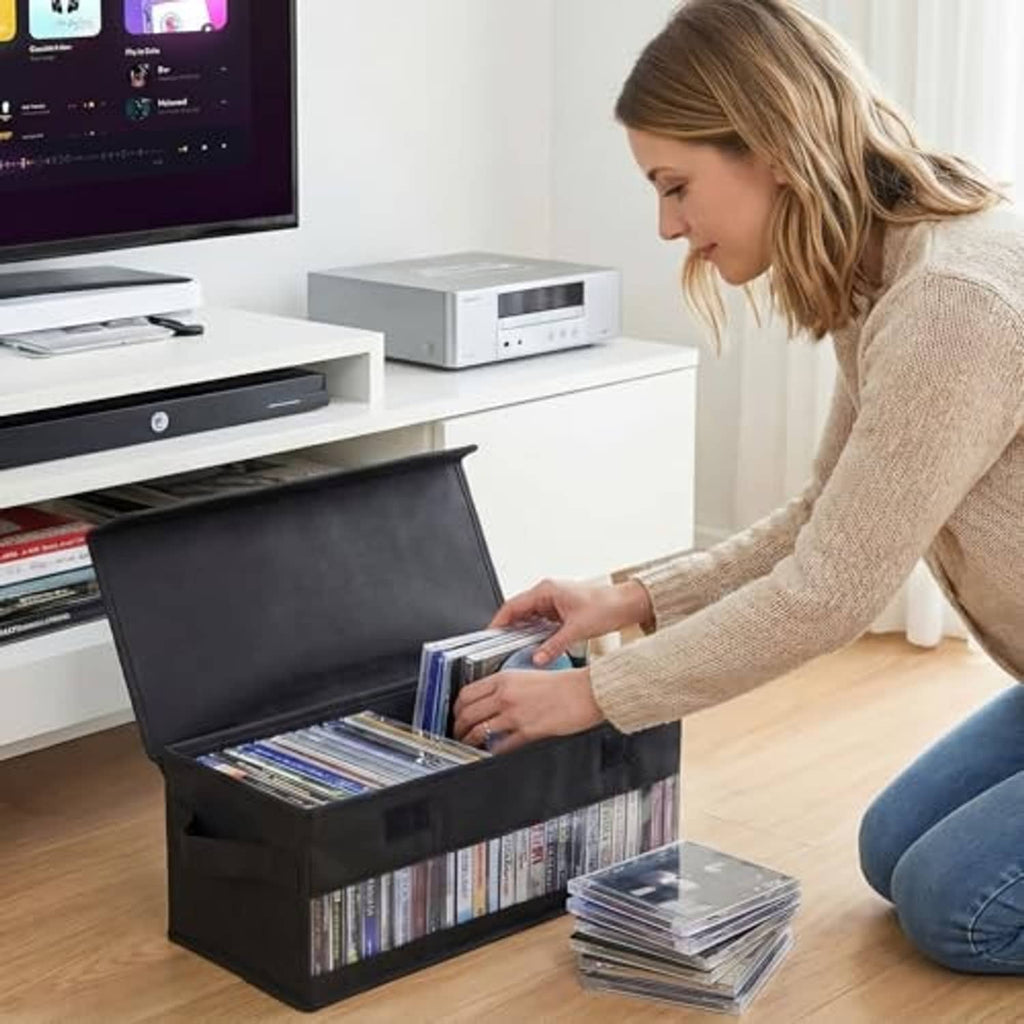 Black CD storage box open with flip-top lid; CDs visible inside from side handle