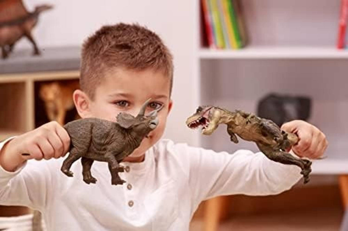 Child holding a Compsognathus dinosaur figurine alongside another dinosaur figure.