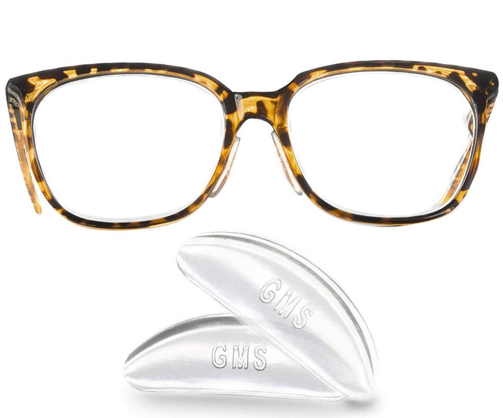 Clear contoured adhesive silicone nose pads beside eyeglasses