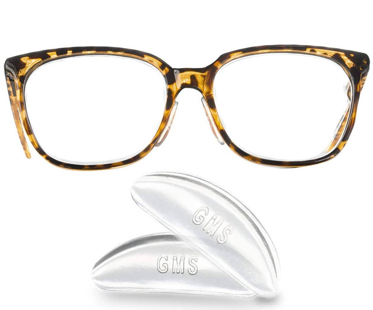 Clear contoured adhesive silicone nose pads beside eyeglasses