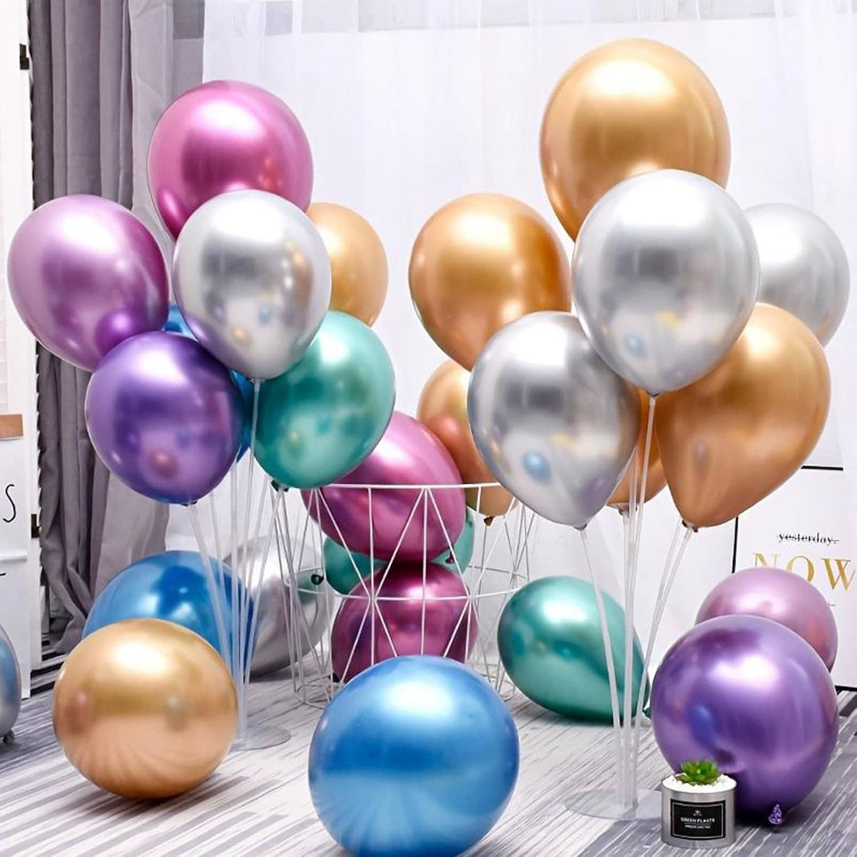 Transparent balloon stand with round base holding purple, teal, and gold balloons