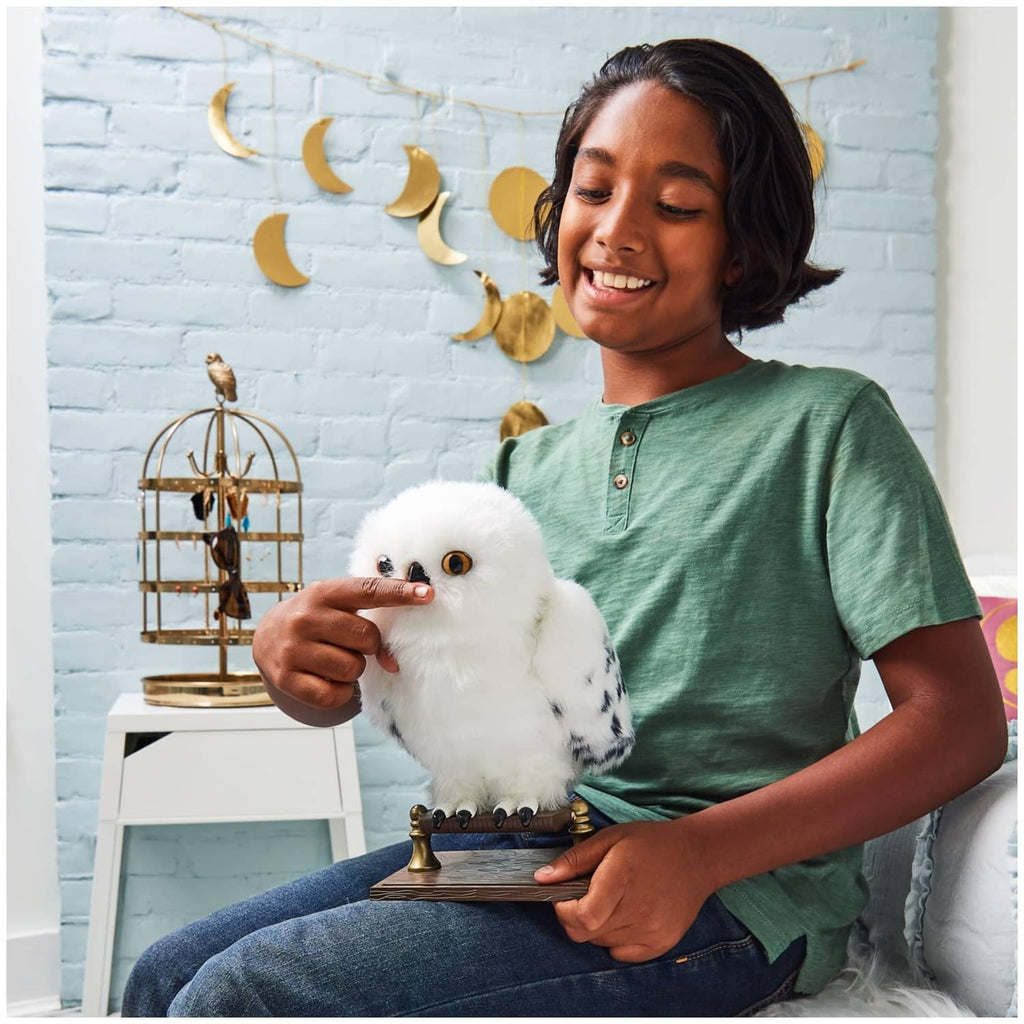 White interactive owl plush on a stand with a person holding it near their face.