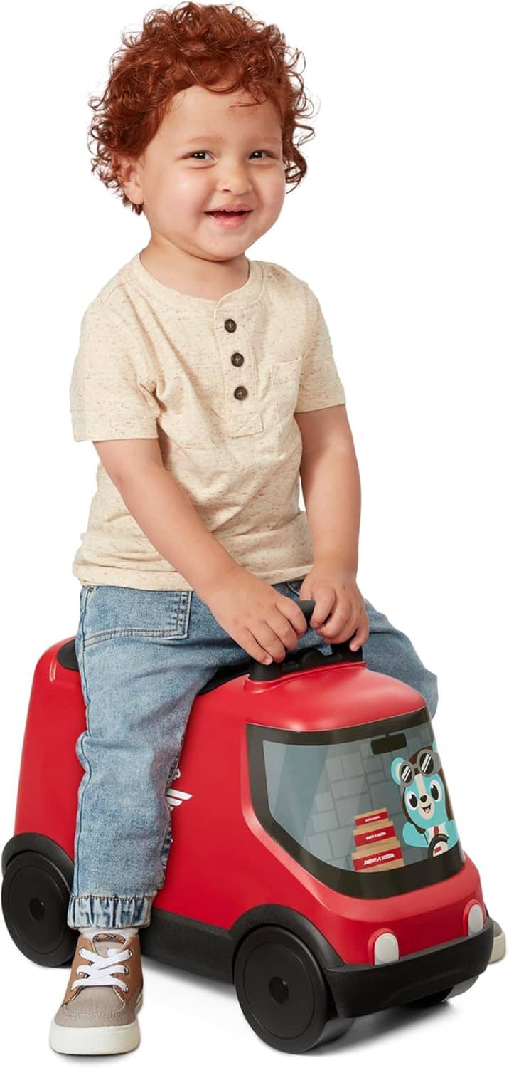 Red ride-on delivery truck toy with clear window; toddler seated holding steering handle