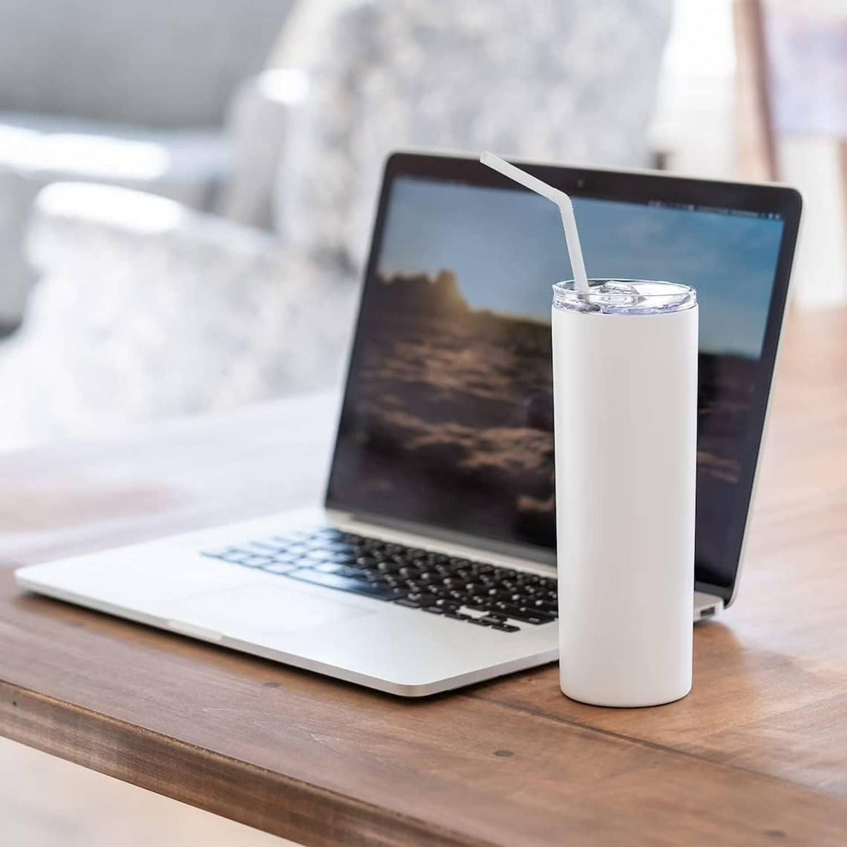White PLA straw cup beside laptop on a wooden table