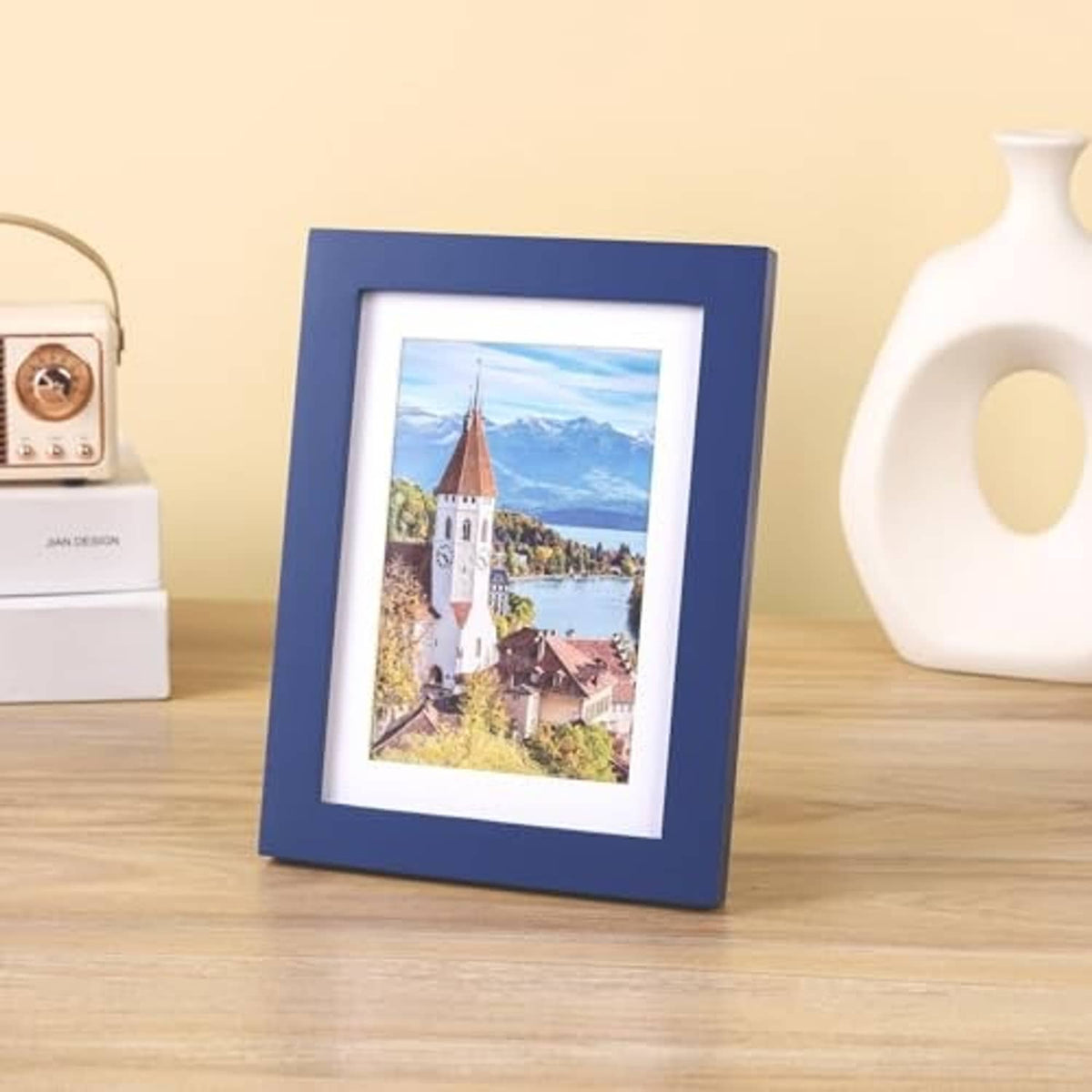 Dark blue solid wood photo frame with white mat, standing on tabletop