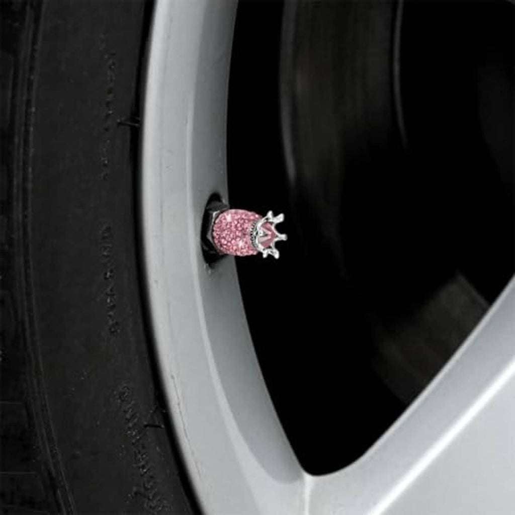 Close-up of a pink rhinestone crown valve stem cap on a wheel, silver crown top