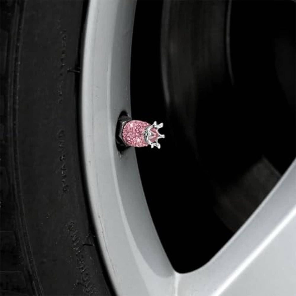 Close-up of a pink rhinestone crown valve stem cap on a wheel, silver crown top