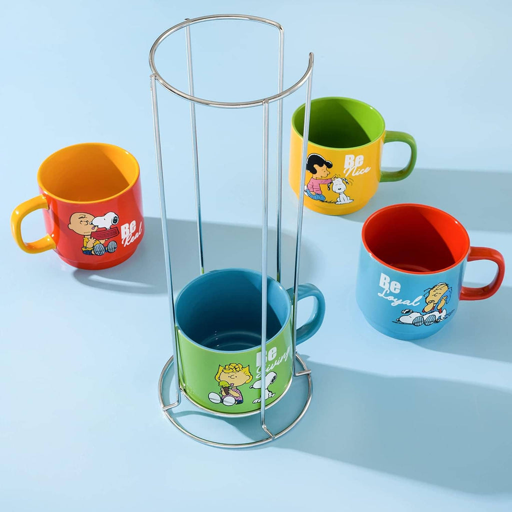 Four Snoopy stoneware mugs with tall metal rack stand, bright colored be-themed artwork.